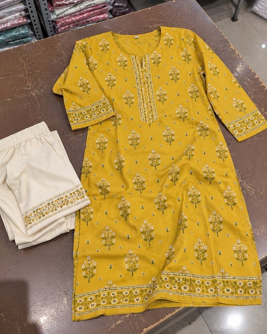 A hurried phone photo of the mustard floral kurta, creased and loosely laid on a packing table