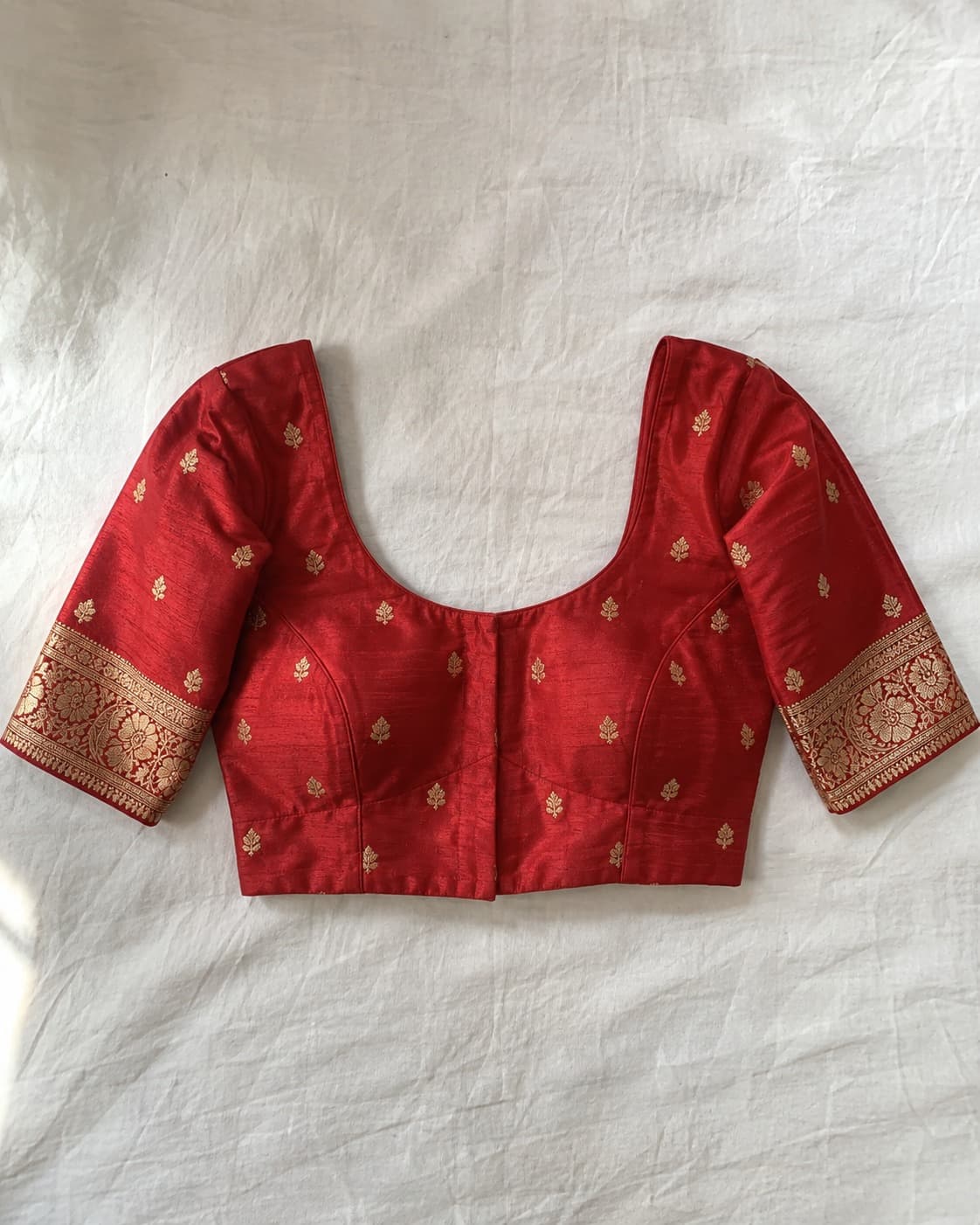 The red and gold SK-114 blouse laid out on cream cloth