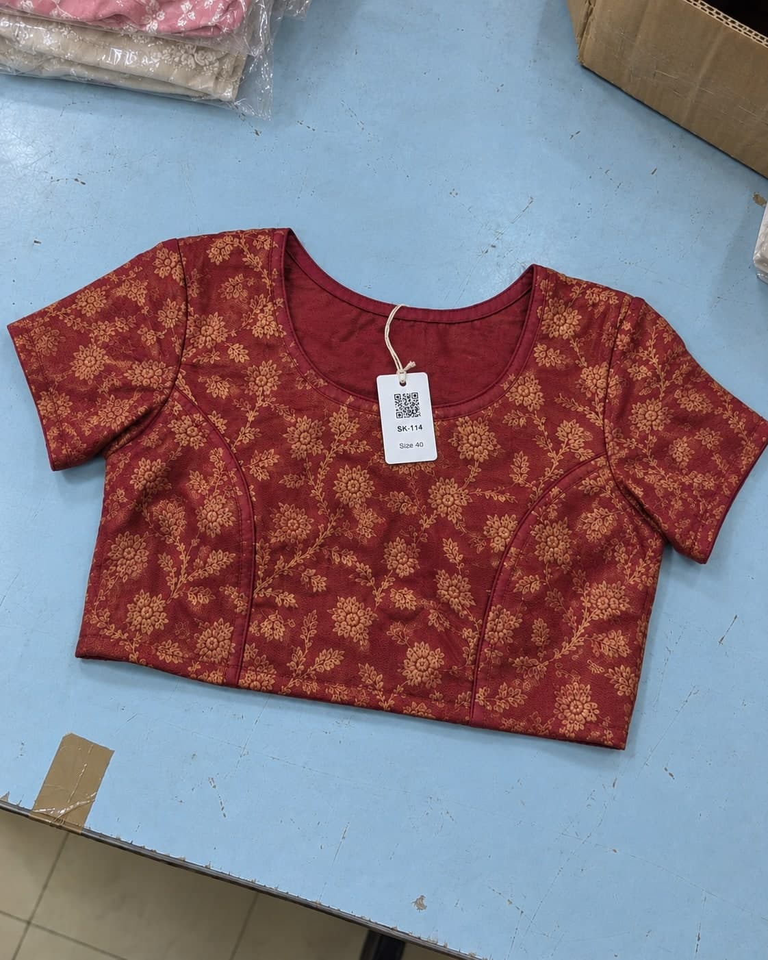 A red and gold blouse laid out unwrapped on a packing table