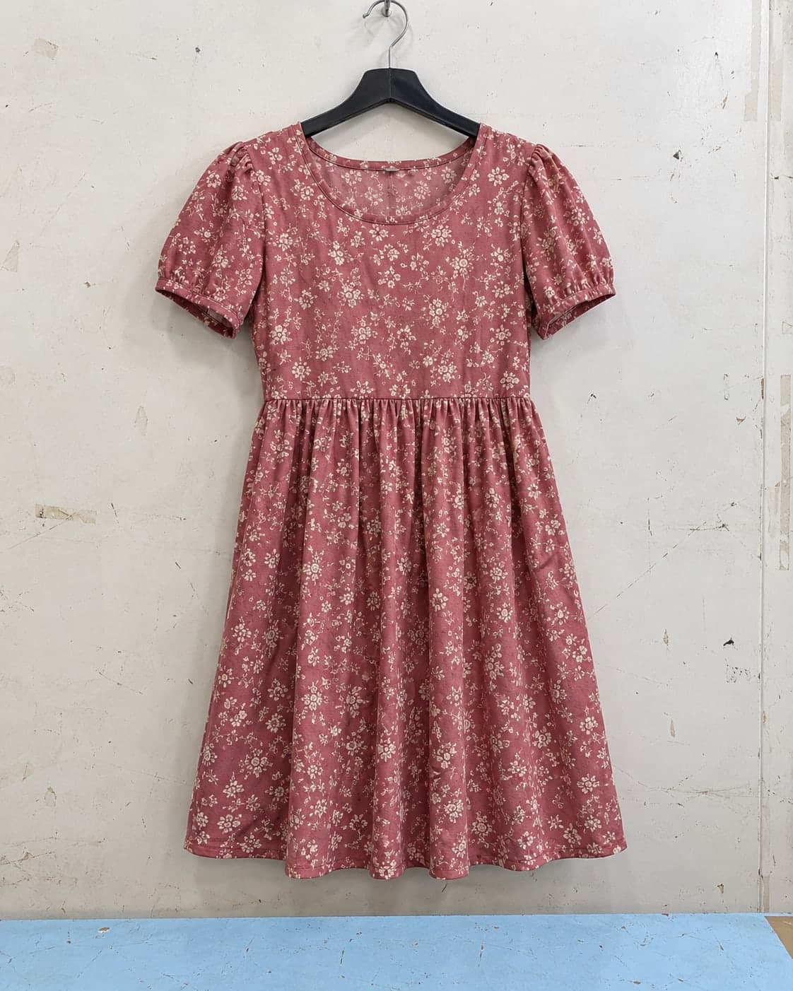 A dusty rose floral dress on an ordinary shop hanger